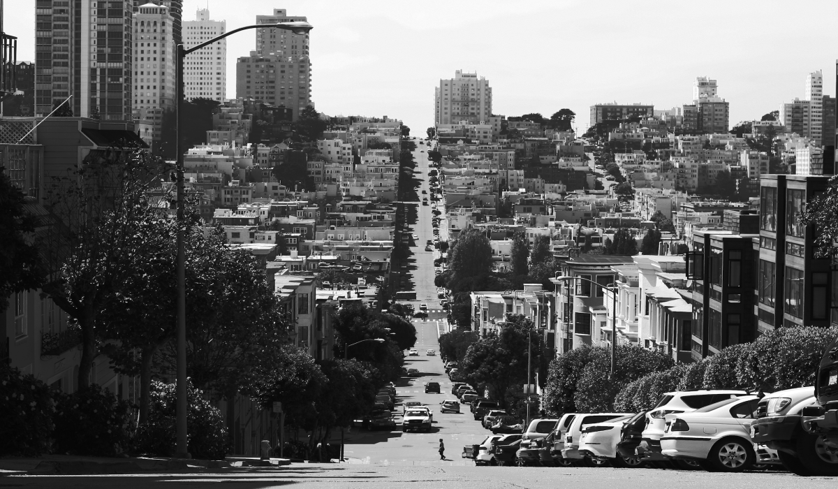 Dramatic Perspective: A Steep, Gray-Paved Road Stretching Through High-City Buildings