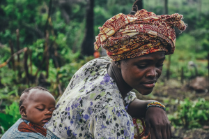 Motherhood in Nature: Woman Carrying Baby on Her Back in a Rural Setting