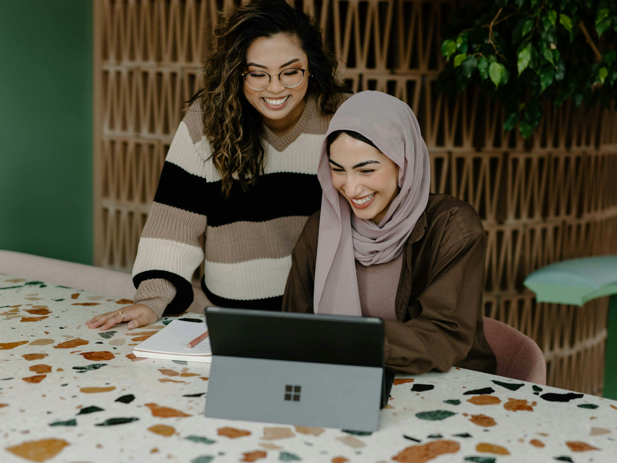 Multi-Cultural Collaboration: Women in Striped Sweater and Hijab Discussing Over Laptop