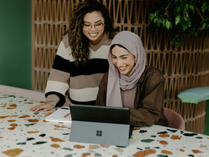 Multi-Cultural Collaboration: Women in Striped Sweater and Hijab Discussing Over Laptop