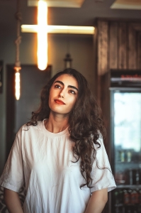 The Mesmerizing Beauty of a Woman Illuminated by a Unique Cross-Shaped Light Fixture
