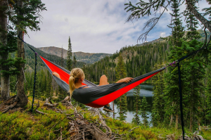 Tranquil Moments: Woman on Hammock by River in the United States - A Captivating Scene by Zach Betten